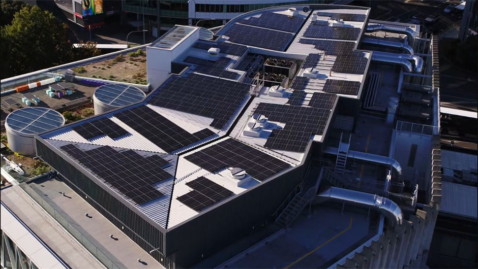 Aerial view of a building with a large solar panel array on the rooftop of a commercial building.